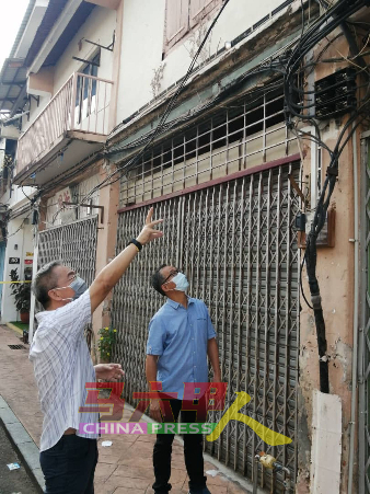 邱培栋（左起）与刘志俍，查看设在老店外墙的电缆。