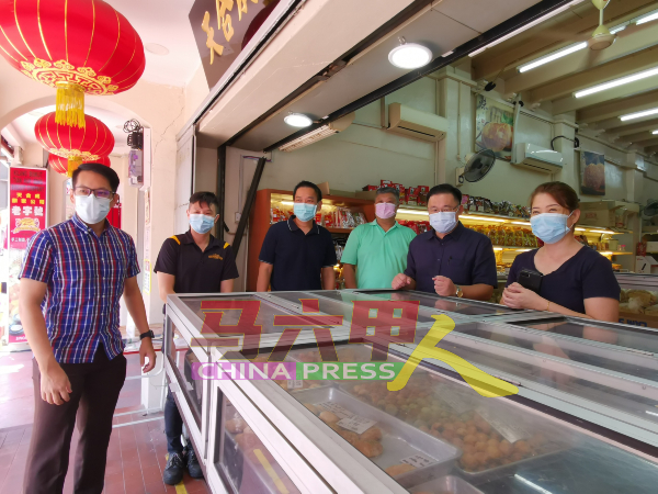 颜天禄（左5）向鸡场街天合成饼家业者林淑萍了解情况及为她加油打气。左起是陈炜建、曾庆辉、吴运就及蔡永泉。