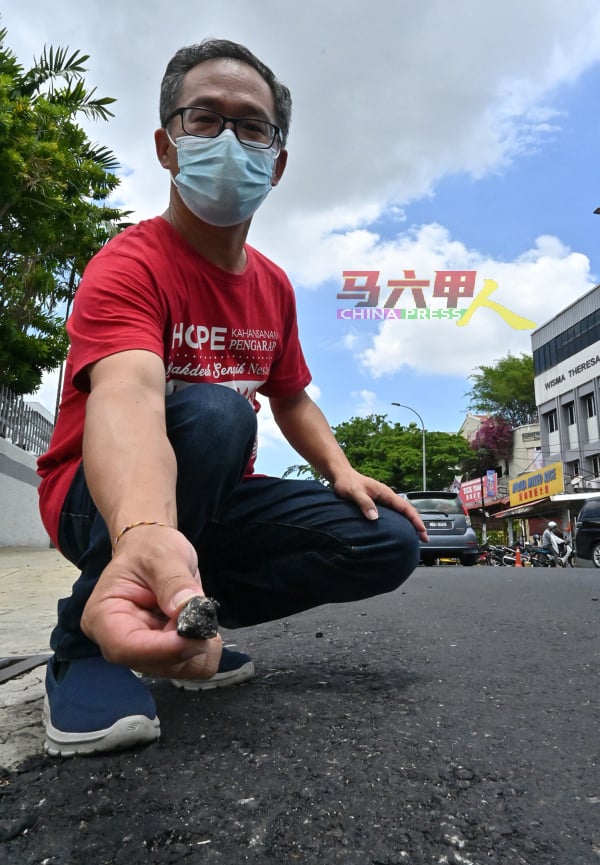 刘志俍在所铺好的路，随手可捡到沥青大石头。