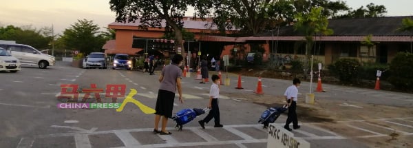 革成学校老师协助维持秩序，让学生安全地步入校园。