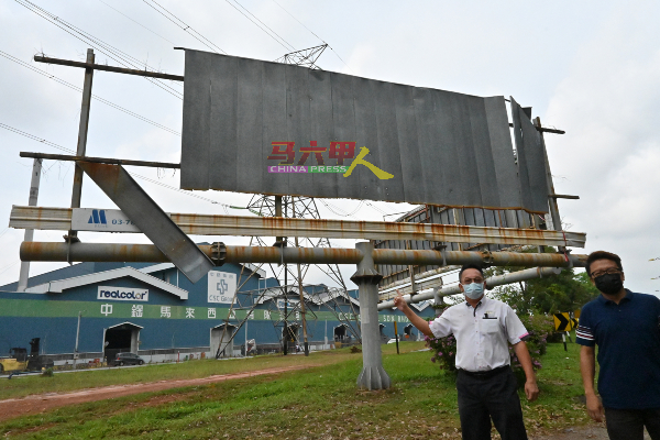 李春源（右起）、叶汉良巡视已毁损的大型广告牌。