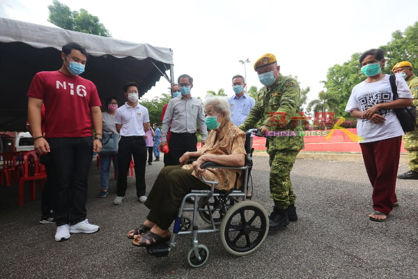 志愿警卫团团员协助推长者进入礼堂。