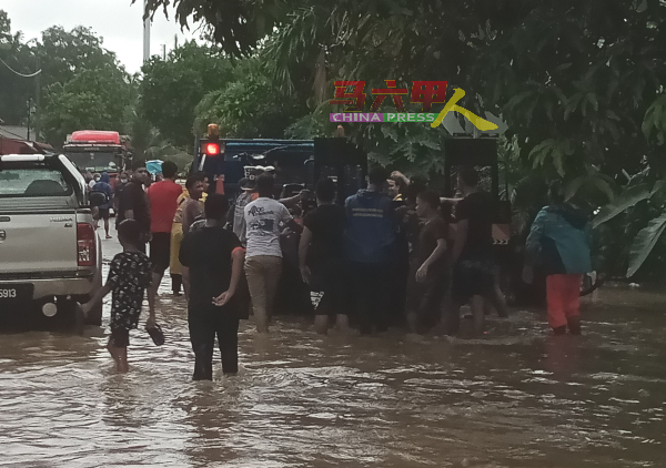 居民合力推动一辆被困于水中的拖车。