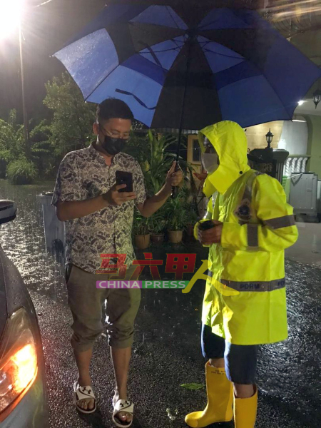 谢守钦（左）凌晨到淹水的默迪卡再也，向一名警员了解水灾情况。