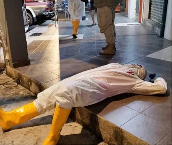 一名消毒队员漏夜完成消毒工作后，直接躺在走廊休息。