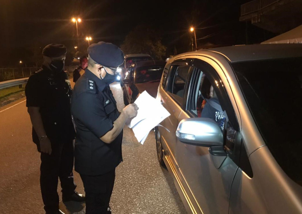■莫哈末赫兹尔（右）向路过的车辆检查外出信函及证件。