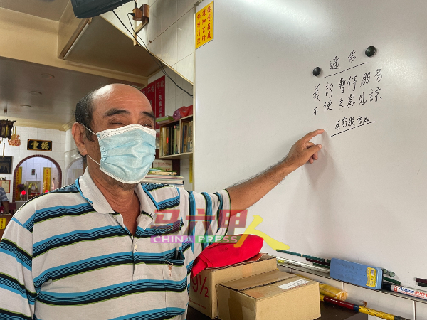 杨士垣向《中国报》展示白板上的通告，以通知民众紫呷阁义诊服务暂停。