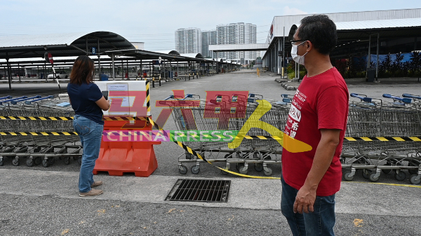 刘志俍（右）看着一名供应商前来拍下霸市关闭的通知，以向上司禀报。