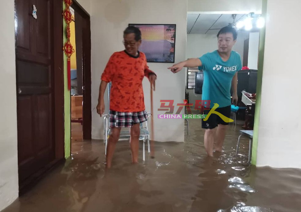 ■余宏（左）与孩子在淹水的住家等水退，方便马上清理。