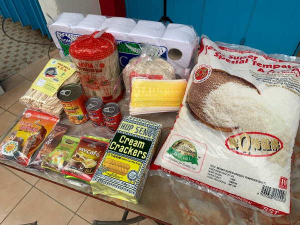 一箱食粮包里的食物和用品，其中包括白米、饼干与卫生纸。