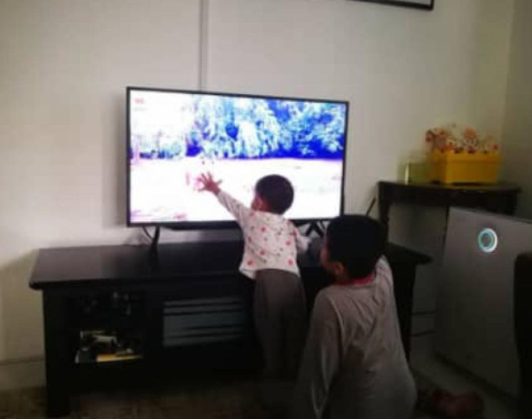 ■孩童通过电视萤幕看动物园直播，看到喜爱的动物时，忍不住上前抚摸。（图取自马六甲动物园面子书）