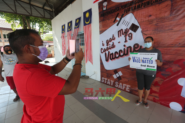 村民手持“我已接种第二剂疫苗”的卡片拍照，作为纪念。