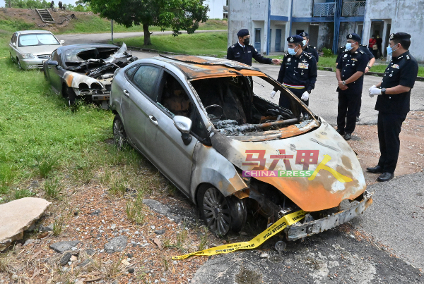 警方在被烧的3辆轿车前召开记者会。