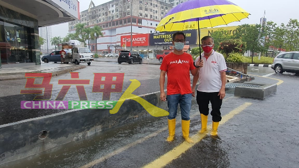 刘志俍（左）指耗资150万令吉的排水系统提升工程（后方）经不起考验。右为陈劲源。