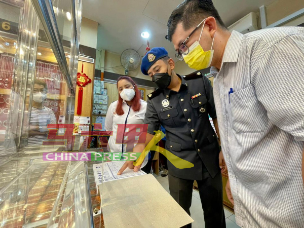 贸消局执法人员检查金饰单据，左是诺丽娜和杨少明（右）。
