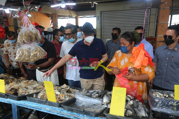 纳吉（中）亲自挑选及购买咸鱼，支持小贩。