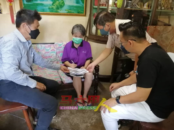 林千宏（左）与蔡求伟（右起）、戴佛淞，协助和见证黄玛莉在社会福利局援助金表格上签名。