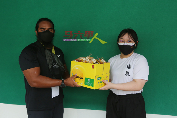 ■培风中学学生代表吴宇萱（右）移交食物给阿布扎，感谢工作人员的付出。