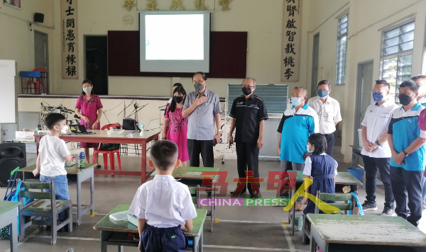 马汉顺（前排左2）在校长、董家协成员及教育局代表等人陪同下，巡视一年级学生上课的情况。