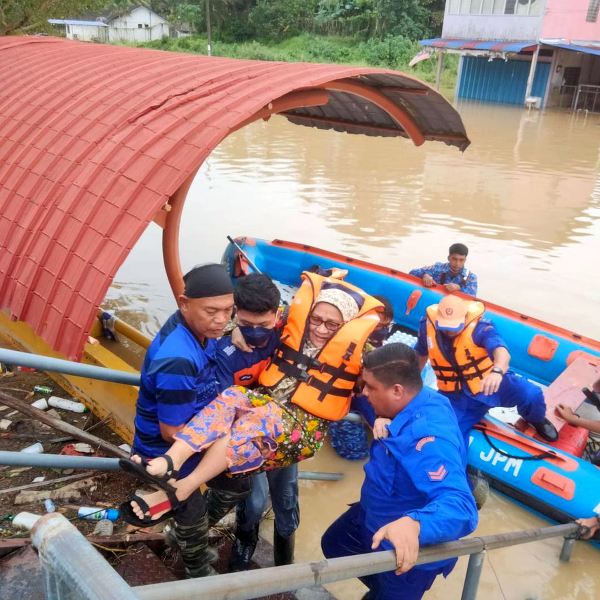 民防人员在发生水灾的甘榜救出居民。（图民防局提供）