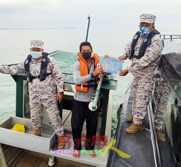 大马海事执法机构人员把安全手册交给渔民。