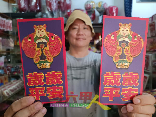 陈益龙向《中国报》读者展示印有虎娃风筝，岁岁平安的剪纸红包封。