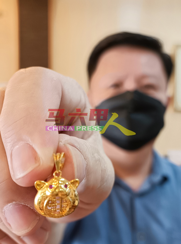 赖乃能向《中国报》记者展示该铺售卖的金虎算盘吊坠。