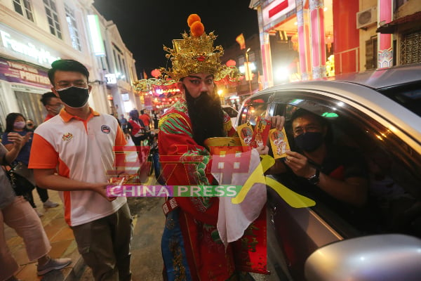 驾车路过的民众，抓紧机会向财神爷讨红包。