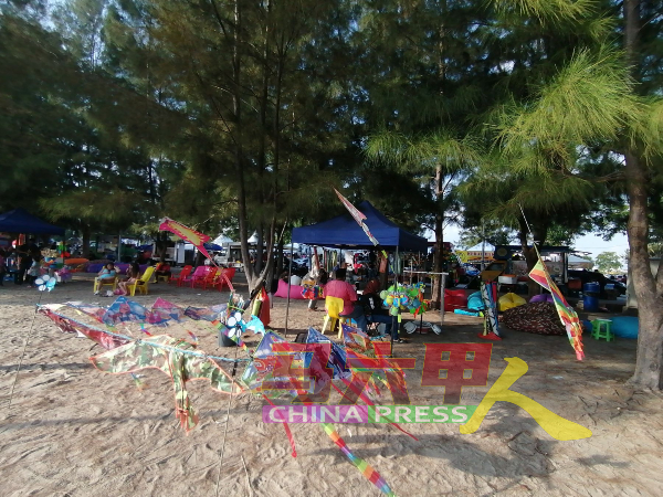 风筝小贩在海边摆卖，访客的到来也为小贩带来商机。