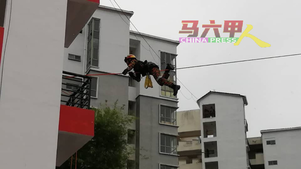 一名消拯员通过一条绳索，由一栋建筑物前进至另一栋楼。