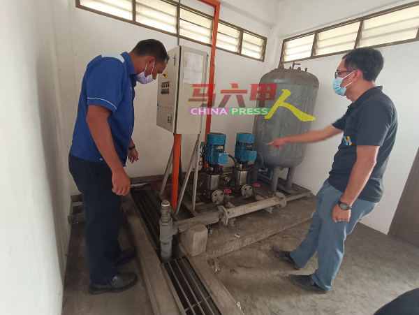 李翰霖（右）与水务公司技术员检查泵水机及水压。