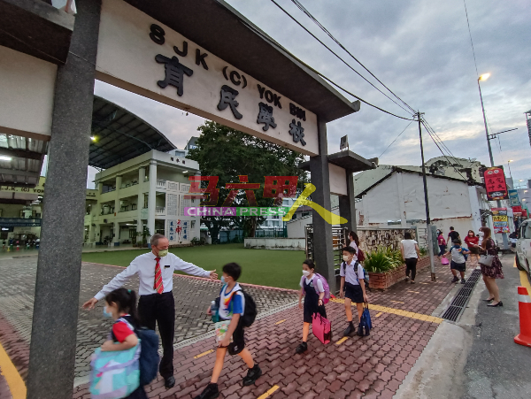 ■育民小学校长郑国华亲自引导学生保持身距，步入学校。