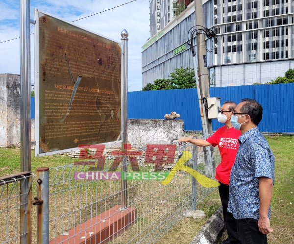 刘志俍（右起）与李祥生查看告示牌内容，发现告示牌已破损及模糊不清。