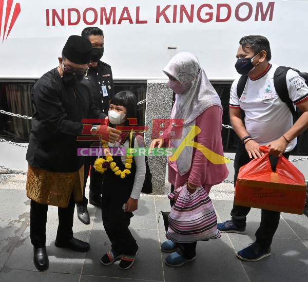 贾拉尼（左）为首批抵达马六甲关税、移民与检疫大厦码头的印尼游客戴上花环。后排为阿尼旺弗兹。