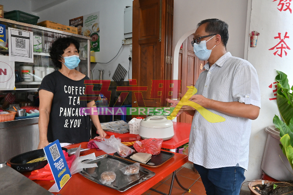 刘志俍（右）向商家了解商店防疫工作。