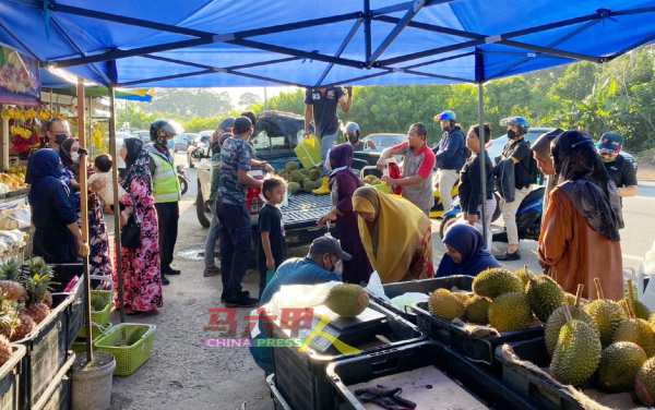 马六甲水果商将甘榜榴梿堆在篮子出售，价格廉宜，吸引成群榴梿饕客到来抢购。