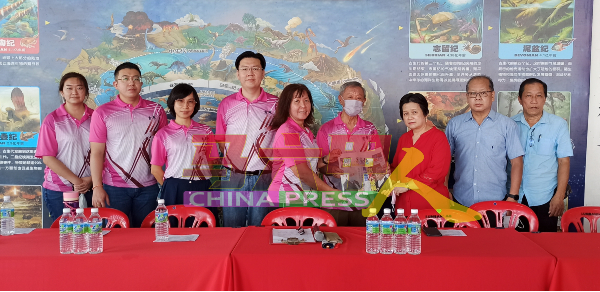 郑春美（中）在该校董家协理事成员的见证下，从陈淑琴（右3）手中接过《中国报》。