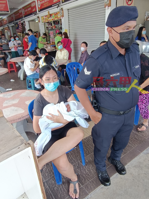 女小贩在警察的保护下，暂时身兼保姆保护婴儿。