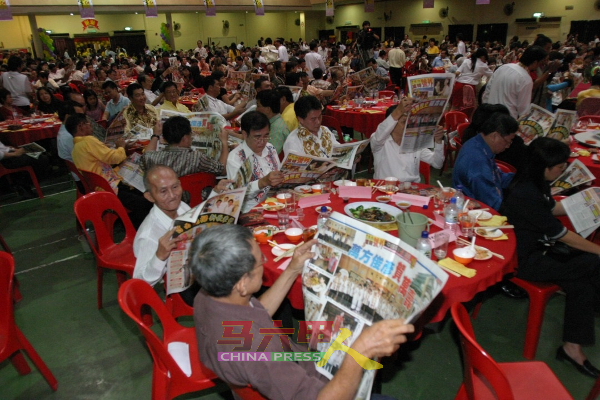余安坚（面向镜头第一排左，白衣者）出席《中国报》60周年报庆晚宴，在会上阅读当晚号外报导。（档案照）