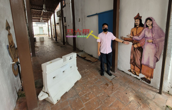 陈炜建指着古里街小巷入口处，两名穿着马来传统服装的人物画像，欢迎游客到来欣赏壁画。