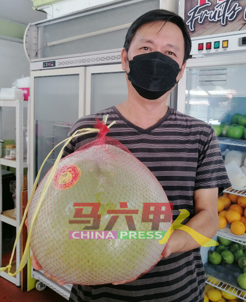 吴云祥手上的神山柚子超过4公斤，他说，通常神庙会买重量级的柚子来拜神。