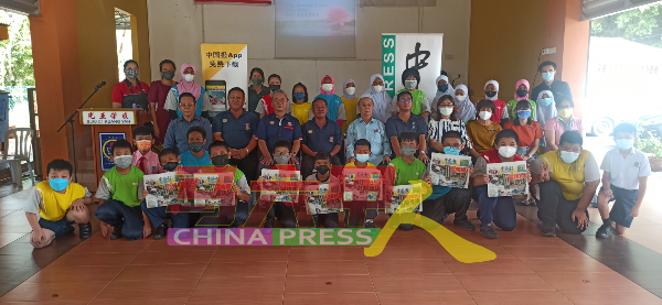 受惠学生举起手中的《中国报》，与嘉宾们合照。