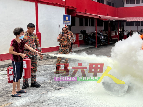 参与讲座者在消拯人员的协助下，学习使用灭火器。