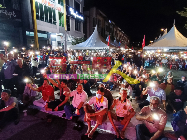 安华在台上歌唱竞选歌曲《Aduh Malaysia》，台下许多民众响应高歌，并亮起手机灯光。 