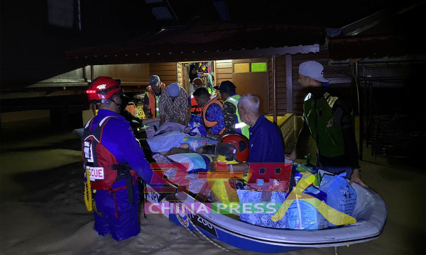 民防局队员使用拯救船，把年长的灾民带离家园。（照片由民防局提供）
