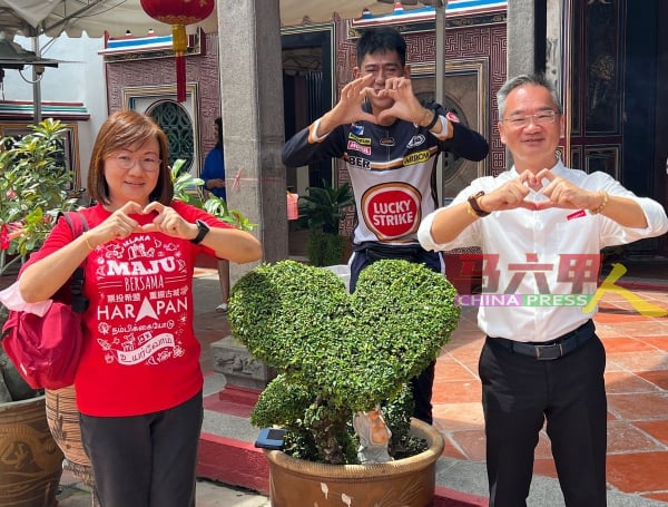 邱培栋（右）与太太李慧贞（左）上香时遇到青云亭志介绍其修剪象征“佛心”的植物，齐齐比心打卡拍照。