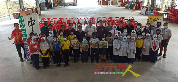 三育华小学生举起手中的《中国报》，与嘉宾们合照。