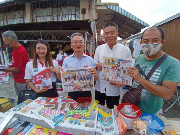 邱培栋（右3）拜访报摊，翻阅《中国报》了解大选时事新闻。左为林朝雁及郑国球（右2）。