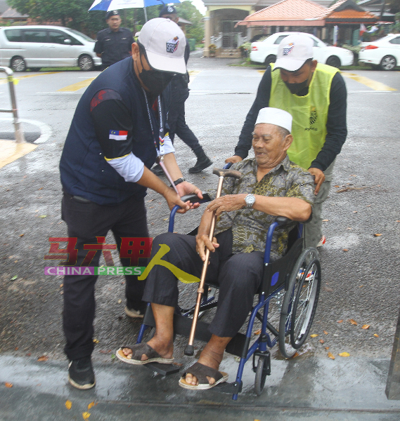 行动不便的年长者坐轮椅到来投票，并获得选委会成员协助。