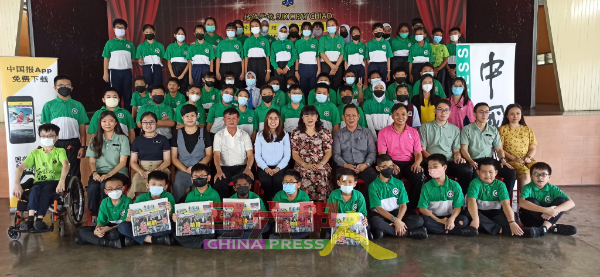 受惠同学开心地举起《中国报》，与嘉宾们合照。